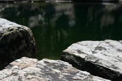 Broken rocks colored with lichen near a lake. 