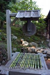 An old wooden water well in a Japanese garden, covered by bamboo stalks strung together. 