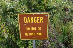 Danger sign near Wailua Falls. Locals use it for target practice. It reads: “Danger. Do not go beyond wall. State of Hawaii Department of Land & Natural Resources.” 